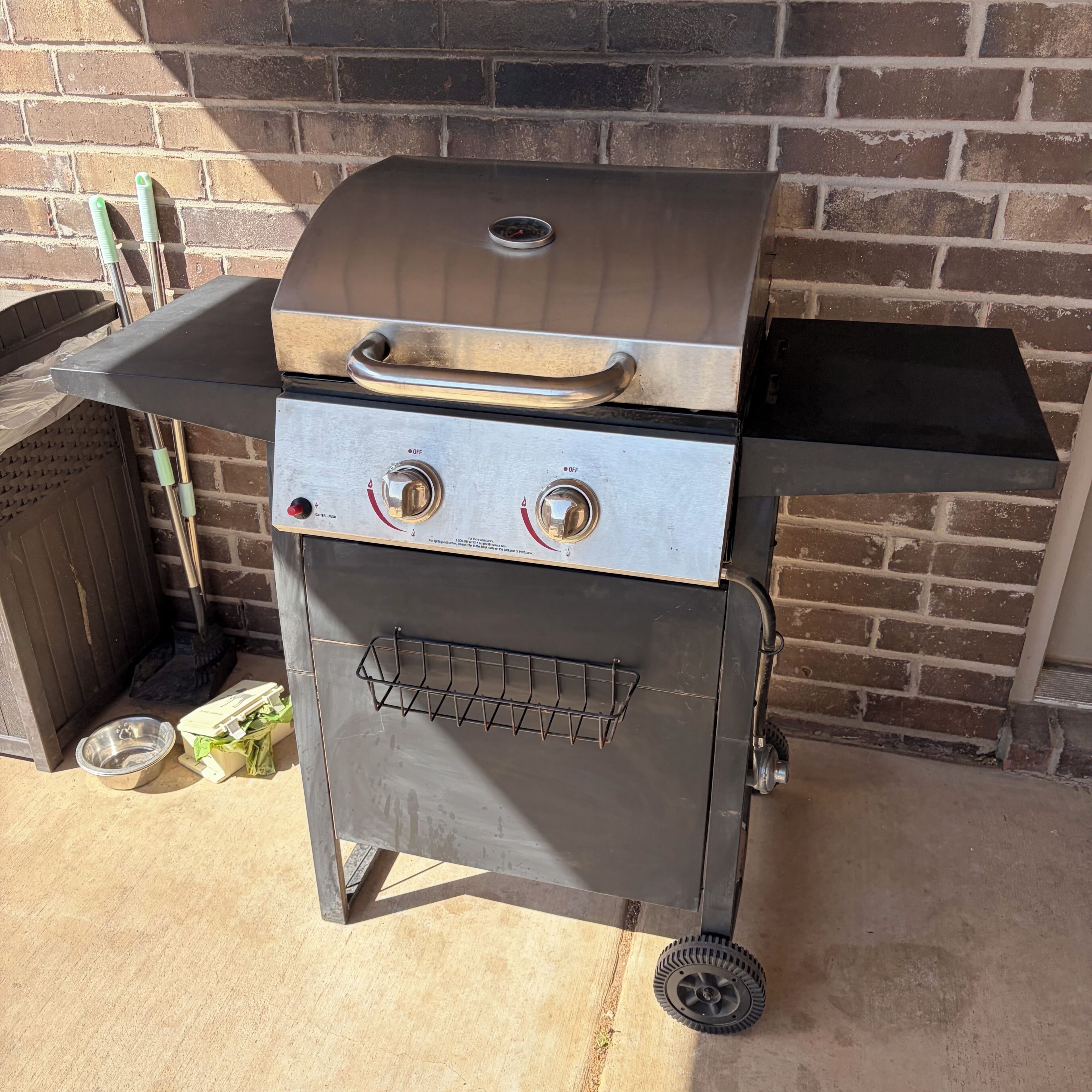 A portable grill with a control panel, a metal rack, and a wheel base.