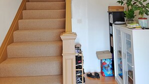 A carpeted staircase with a wooden handrail, a potted plant on the landing, and a small table with items on it. - 9 - Peaceful & Spacious 4B2B Upper Unit near FW (Daly City)