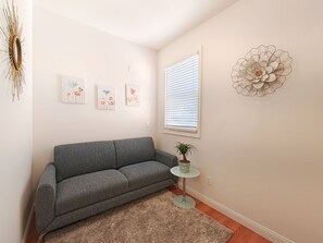 A living room with a grey sofa, a small round table with a plant, and three floral artwork on the wall. - 9 - Peaceful & Spacious 4B2B Upper Unit near FW (Daly City)