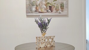 A round dining table with a 'Happy Spring' sign, surrounded by four chairs, set against a wall with a framed floral painting. - 9 - Peaceful & Spacious 4B2B Upper Unit near FW (Daly City)