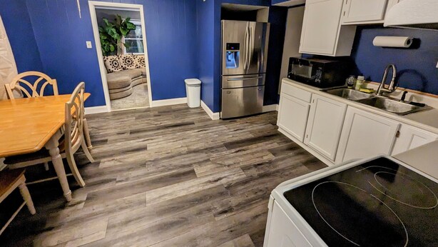 Una cocina moderna con armarios blancos, un refrigerador de acero inoxidable y un microondas.