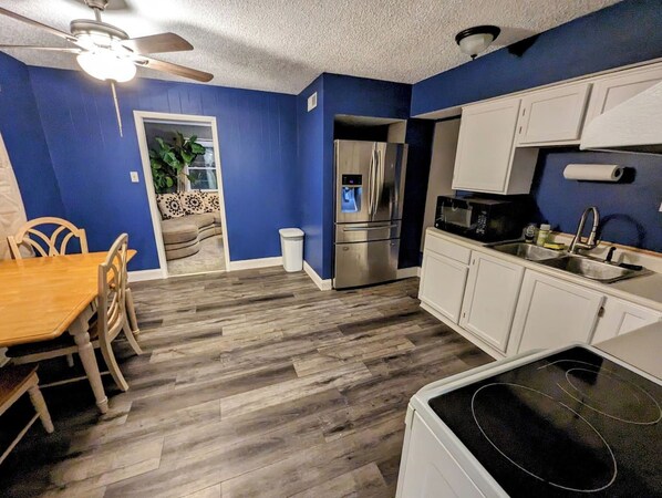 A compact kitchen with a refrigerator, microwave, and white cabinets. - 3BR | Fully Fenced Front & Back Yards | Fast WiFi (Evansville)