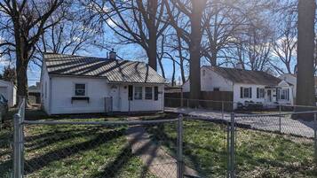 A fenced property with multiple single-story houses, a clear sky, and a pathway leading to the houses.