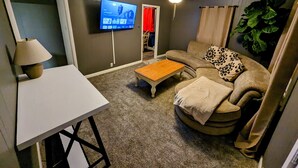 Una sala de estar con televisor, mesa, sofá y ventilador de techo.
