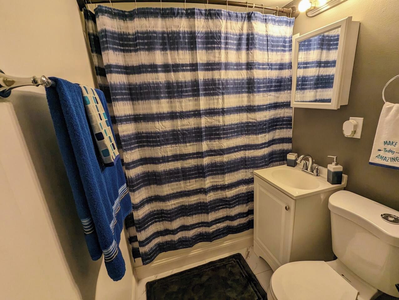 A bathroom with a striped shower curtain, a sink, a toilet, and a towel rack.
