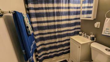 A bathroom with a striped shower curtain, a sink, a toilet, and a towel rack.