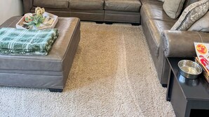 Un salon avec un canapé en cuir marron, une table basse et un tapis.