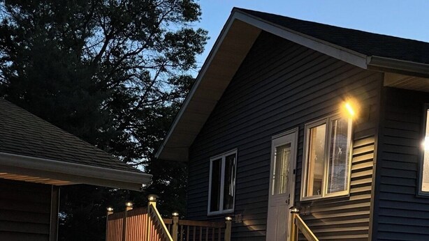 Une maison à deux étages avec un escalier en bois et une terrasse.