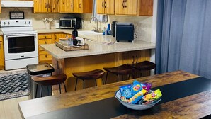 Une cuisine moderne avec des meubles en bois, un îlot central et un coin repas comprenant une table et des chaises en bois.