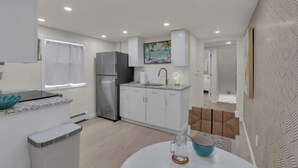 A modern kitchen with white cabinets, a stainless steel refrigerator, and a window with white curtains. - Seaside Heights' Palm Tree Paradise: 3BR (Seaside Heights)