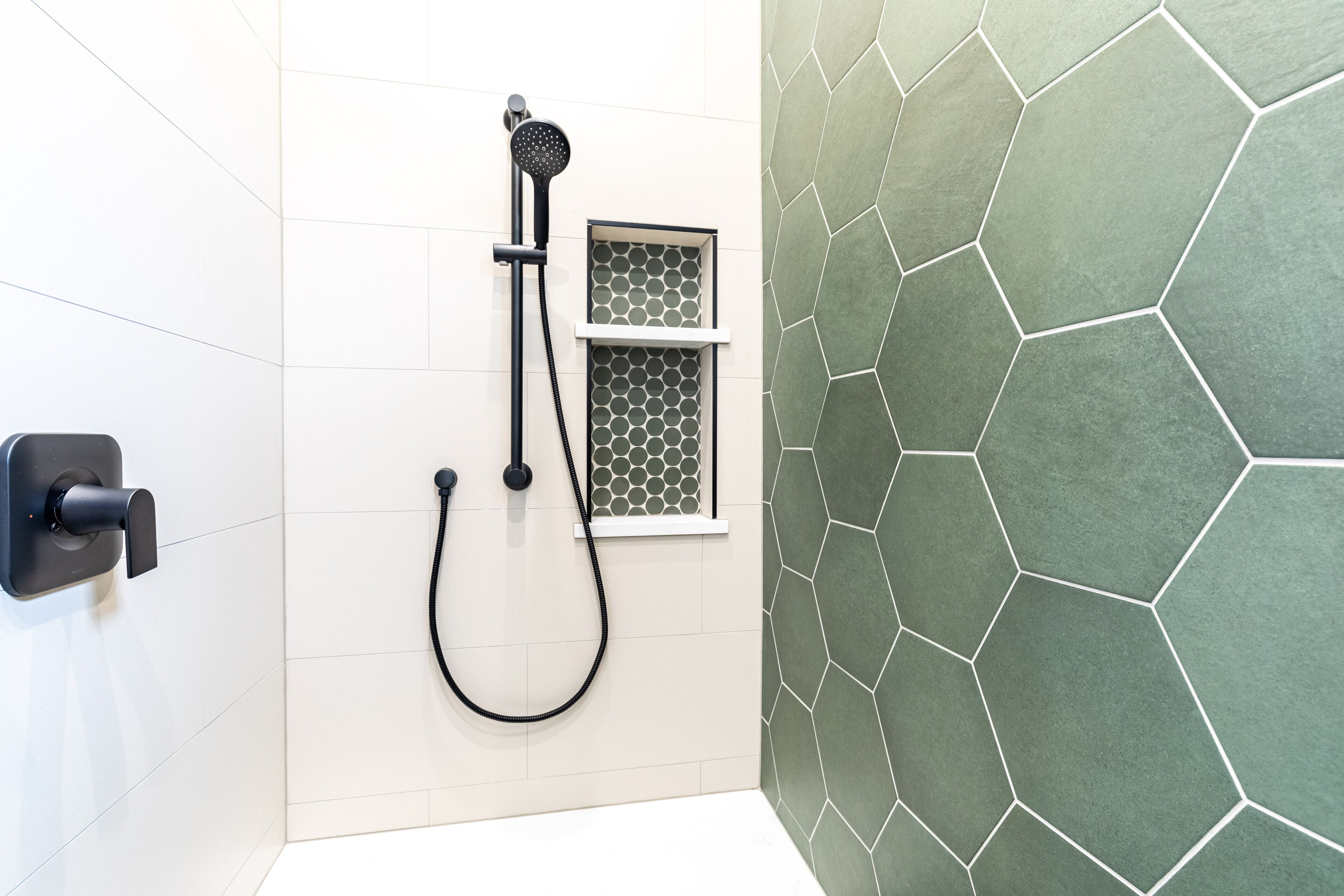 Een douche met een handdouche en een bedieningspaneel aan de muur.