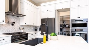 Cocina moderna con armarios blancos, un refrigerador negro, un horno Bosch y un lavamanos con grifo negro.