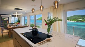 Une cuisine moderne dotée d’un grand îlot central, d’une bouilloire et d’un vase rempli de fleurs.