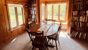 Un interior de madera con una mesa de comedor, sillas, estanterías y un ventilador de techo.