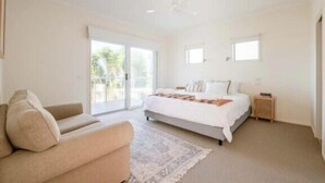 A bedroom with a bed, a sofa, a nightstand, and a window. - Salty Ocean View Escape - Torquay (Surf Coast)