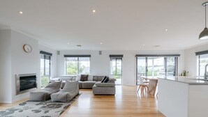 A spacious living area with a sofa set, a dining table, and a kitchen area with a sink and counter. - Torquay Beach Holiday Homebase (Surf Coast)