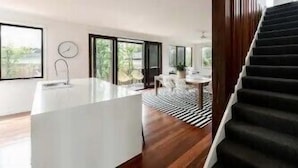 Ein modernes Interieur mit Kücheninsel, Essbereich und Treppe.