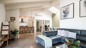 A spacious living area with a grey sofa, a coffee table, and a dining area in the background. - Country Seaside Escape - Torquay (Surf Coast)
