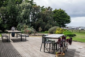 An outdoor deck with a table and chairs, surrounded by greenery and trees. - Country Seaside Escape - Torquay (Surf Coast)