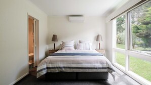 A bedroom with a bed, two bedside lamps, a window, and a door. - Country Seaside Escape - Torquay (Surf Coast)