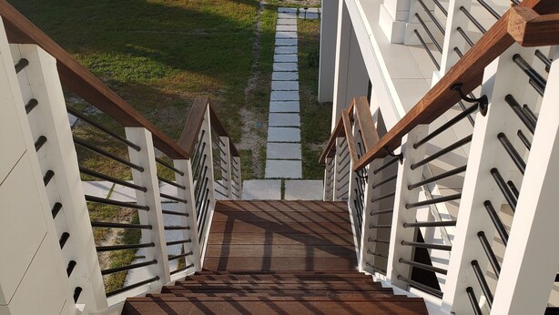 Un escalier avec des rampes blanches et des marches en bois menant à un palier.
