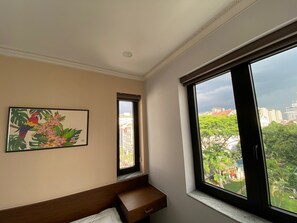 Enjoy city views from the large window in this stylish room featuring a comfortable bed, bedside table, and artwork.