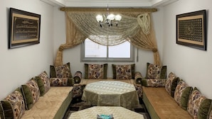 A room with two round tables, each surrounded by a sofa with floral cushions. There are framed calligraphy pieces on the walls. - Spacious 3-bedrooms apartment (Tétouan)