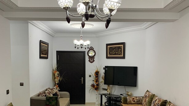 A living room with a round coffee table, sofas, a TV, and a chandelier. - Spacious 3-bedrooms apartment (Tétouan)