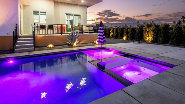 Ein modernes Haus mit Swimmingpool, Sitzgelegenheit im Freien und Blick auf Berge.