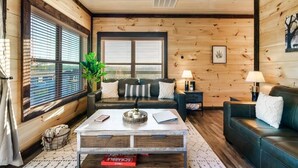 Una sala de estar acogedora con detalles de madera, un sofá, una mesa de centro y una ventana con persianas.