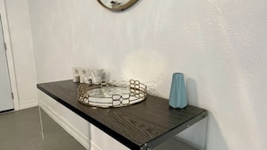 A bathroom with a modern vanity, a round mirror, and a glass shelf with toiletries. - Relaxing Home Near Universal (Orlando)