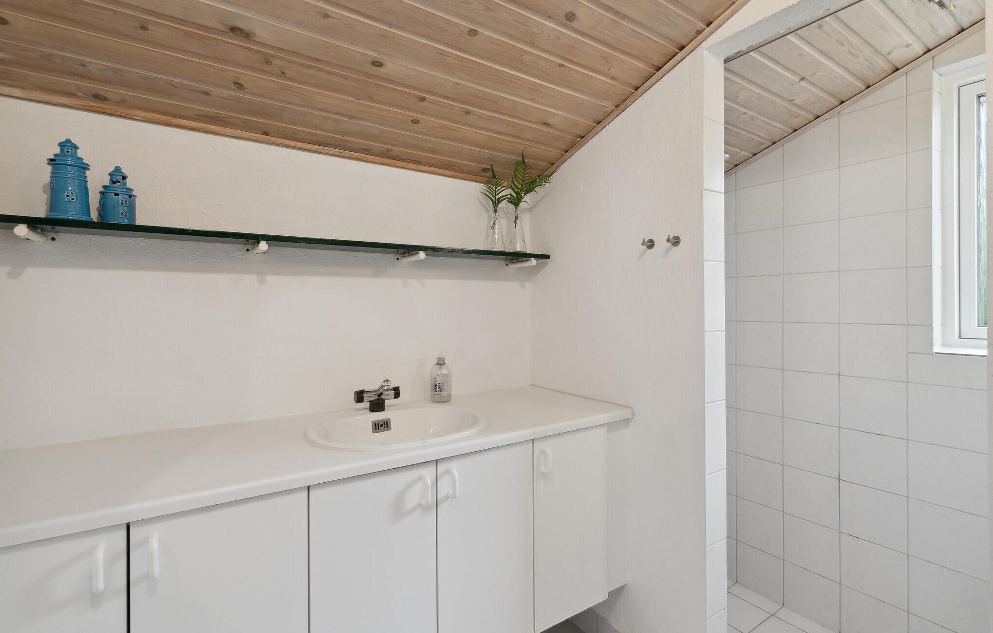 Une salle de bain avec un lavabo blanc, un miroir et un espace douche.
