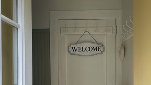 Una porta blanca amb un rètol que diu 'WELCOME', un penjallavedres i un objecte groc a la paret.