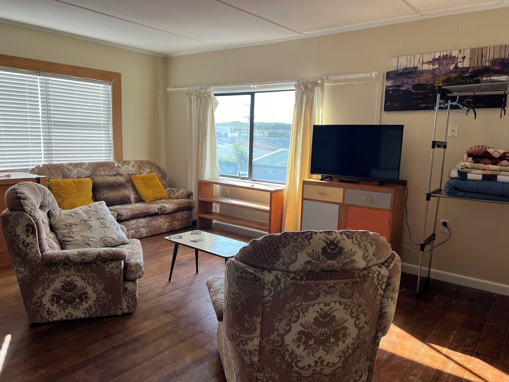A living room with a sofa, armchair, coffee table, and a TV on a stand.