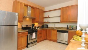 Eine moderne Küche mit Holzausstattung, Edelstahlgeräten und Fliesenboden.