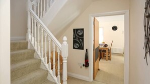 A staircase with white balusters leading to a carpeted floor. A black abstract painting hangs on the wall. A dining area is visible through an open door, featuring a wooden table and chairs. - 3Bed/2Bath Duplex Apartment - Pure Bliss Belfast (Belfast)