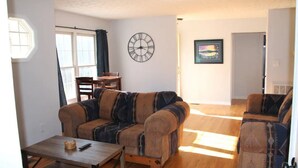 Un salon avec un canapé, une table basse, une horloge et un tableau accroché au mur.