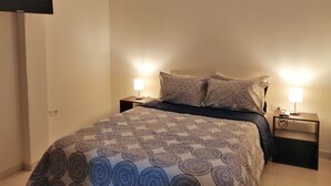 Camera da letto con un letto, due comodini con lampade, una TV a schermo piatto montata a parete e un condizionatore d'aria a soffitto.