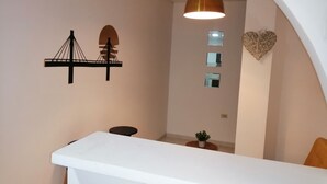 Un interno moderno con una scrivania reception bianca, una lampada a sospensione, una decorazione a forma di cuore appesa al muro e la sagoma di un ponte.
