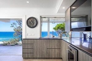 A modern kitchen with a built-in island, a clock on the wall, and a view of the ocean.
