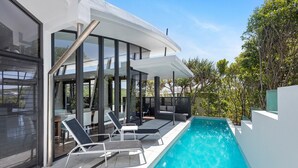 A modern outdoor pool area with lounge chairs and a glass-enclosed patio.