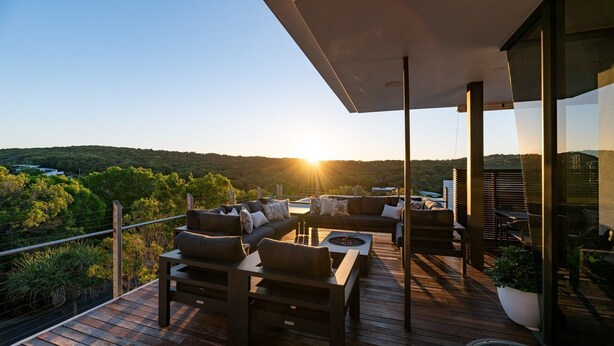 A deck with outdoor furniture and a view of a forested area.