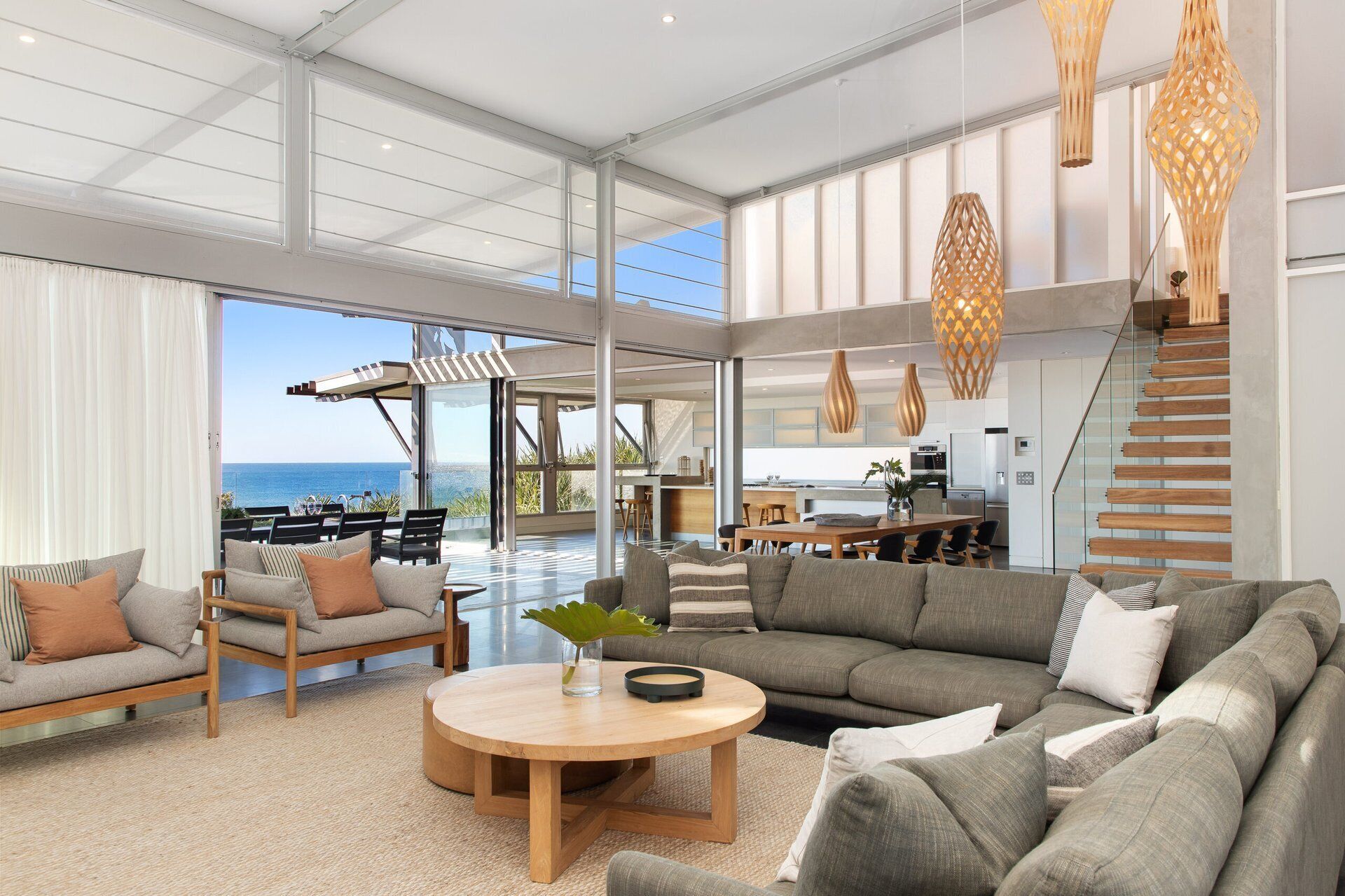A spacious living area with a large sofa set, a coffee table, and a view of the ocean.
