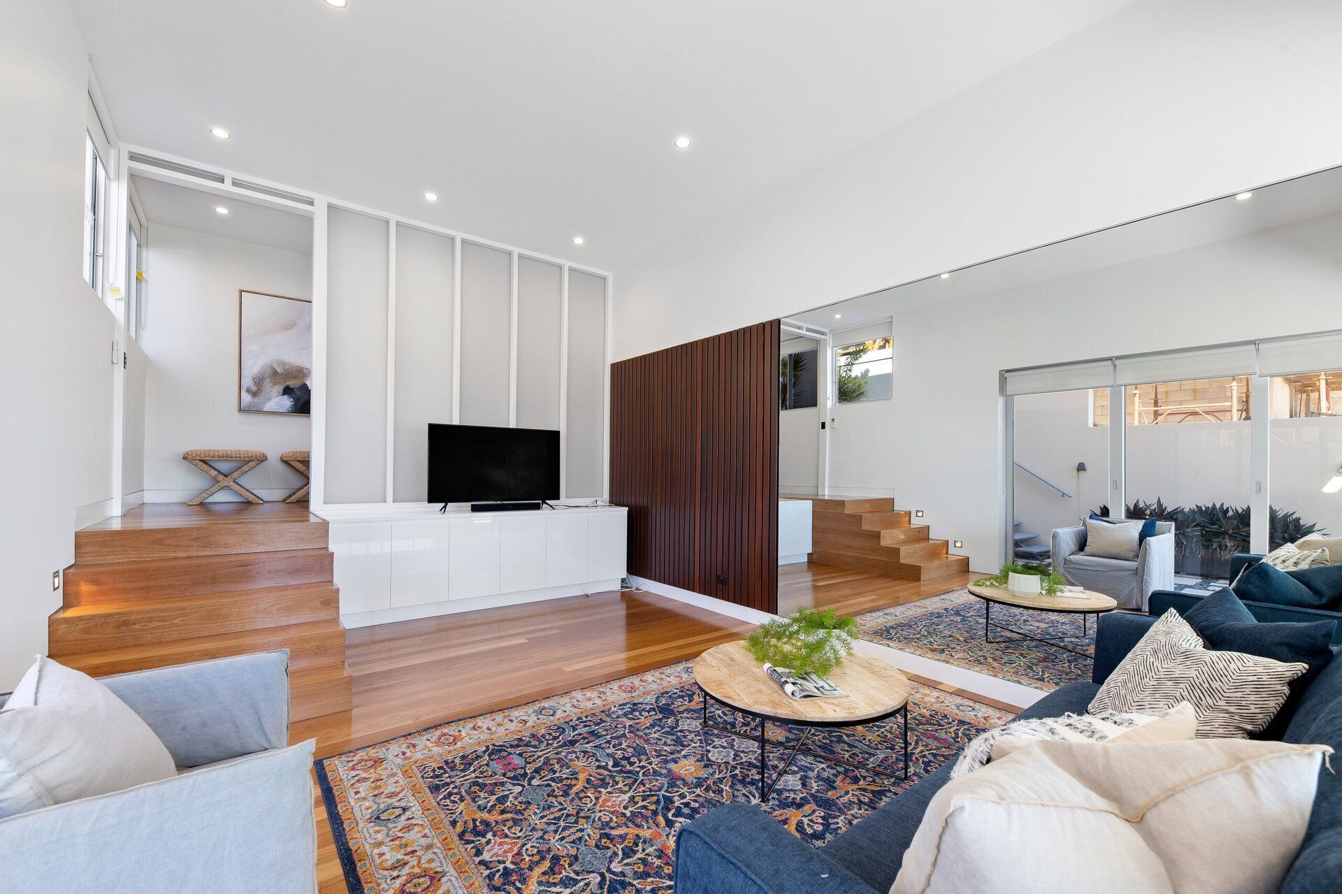 A modern living room with a flat-screen TV, a coffee table, and a sofa.