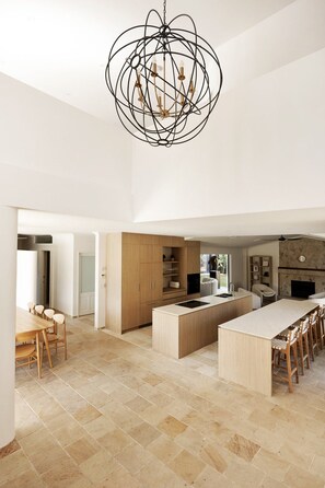 A spacious kitchen with a large island, wooden cabinets, and a unique black chandelier.