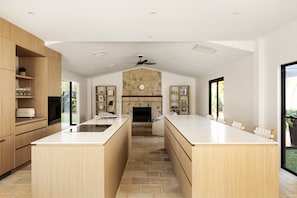 A modern kitchen with a central island, built-in appliances, and a stone accent wall. - Casa Six on Witta near Hastings Street Noosa (Noosa Heads)