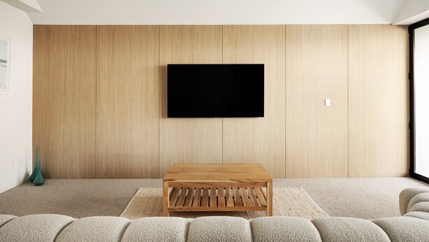 Ett modernt vardagsrum med en platt-TV som är monterad på en väggpanel i trä, ett soffbord i trä och en soffa.