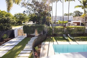 A residential area with a swimming pool, paved pathways, and a variety of trees and shrubs. - Casa Six on Witta near Hastings Street Noosa (Noosa Heads)