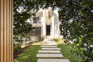 Uma trilha leva a um edifício de design moderno, cercado por vegetação.
