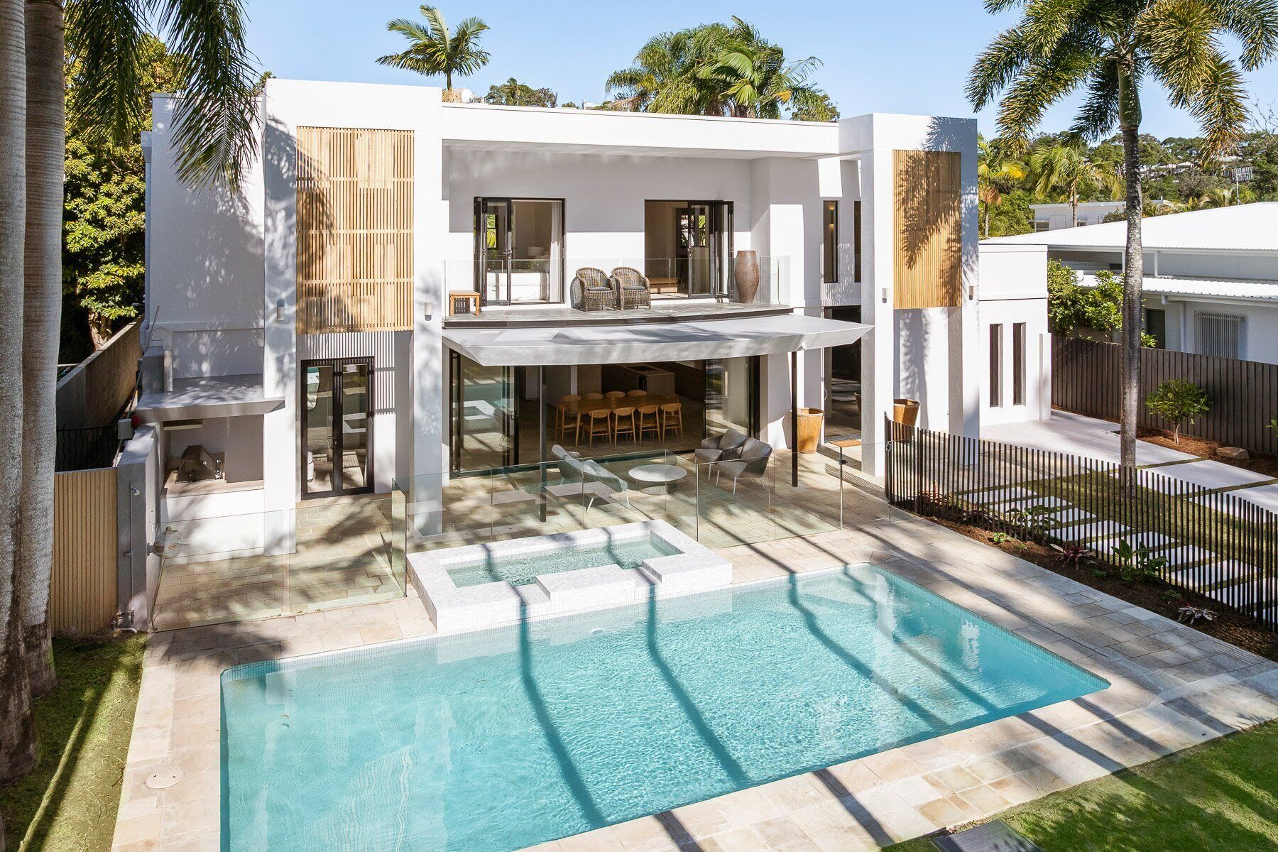 A modern house with a swimming pool, outdoor seating, and a fenced yard.